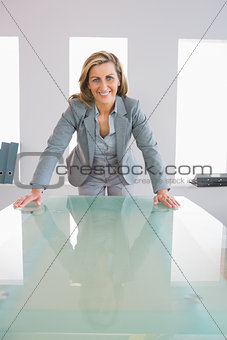 Happy businesswoman standing in front of a desk