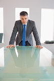 Serious businessman standing in front of a desk