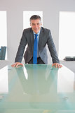 Laughing businessman standing in front of a desk