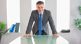 Happy businessman standing in front of a desk