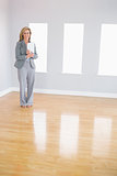 Happy realtor standing in a room holding documents
