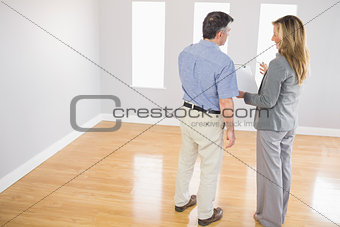 Blonde realtor showing a room and some documents to a potential buyer