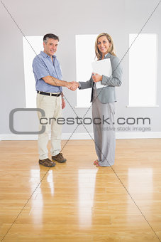 Pleased realtor and buyer shaking hands