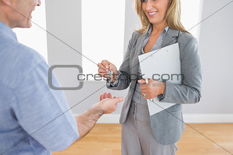 Close up of a smiling realtor delivering a key to a laughing buyer