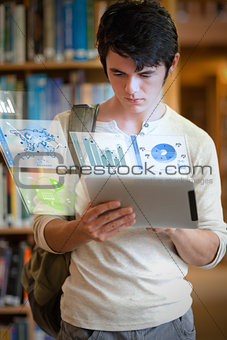 Serious handsome student working on his futuristic tablet pc
