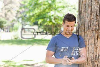 Cheerful handsome student using his digital smartphone