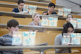 Focused students in lecture hall working on their futuristic tablet