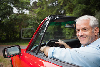 Smiling handsome man driving red cabriolet