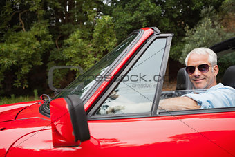 Cheerful handsome man enjoying his red convertible