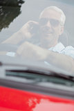 Cheerful handsome man in red convertible having phone call