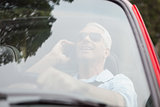 Smiling handsome man in red convertible having phone call