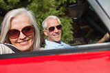 Side view of cheerful mature couple driving red cabriolet