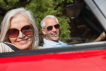 Side view of cheerful mature couple driving red cabriolet