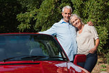 Happy mature couple hugging by their red cabriolet