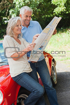 Cheerful mature couple reading map together