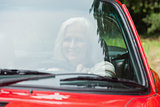 Cheerful mature woman driving red cabriolet