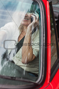 Smiling mature woman on the phone driving red cabriolet