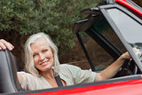 Smiling mature woman posing in red convertible