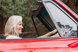 Happy mature woman driving red convertible