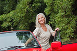 Cheerful mature woman getting off her convertible