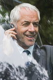 Happy mature businessman on the phone driving
