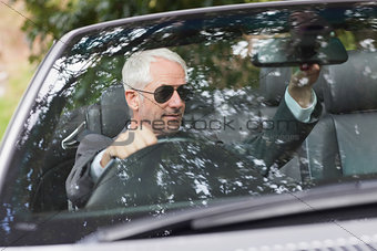 Mature businessman adjusting his cabriolet rear view mirror