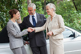 Cheerful business people talking together by classy cabriolet