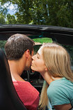 Attractive blonde kissing her boyfriend while having a ride in cabriolet