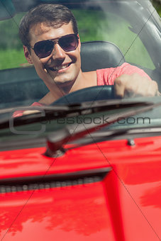Cheerful handsome man driving his cabriolet