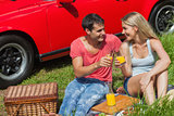 Cheerful couple sitting on the grass having picnic together