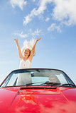 Happy woman standing in cabriolet while her boyfriend driving