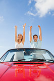 Cheerful couple standing in red cabriolet