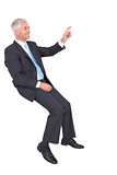 Smiling businessman sitting and pointing finger