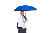 Businessman holding umbrella smiling at camera