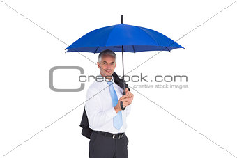 Businessman holding umbrella smiling at camera