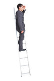 Young businessman standing on ladder looking away