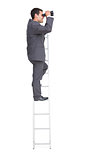 Businessman standing on ladder using binoculars