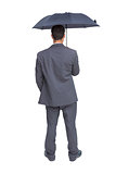 Rear view of classy businessman holding grey umbrella