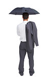 Businessman standing back to camera holding umbrella and jacket on shoulder