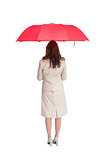 Businesswoman standing back to camera holding red umbrella