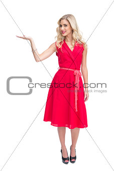 Cheerful woman in red dress presenting something in her hand