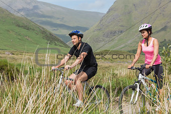 Athletic couple biking through countryside