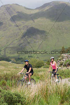 Athletic couple biking through wilderness