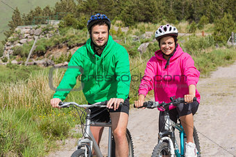 Happy couple on a bike ride wearing hooded jumpers