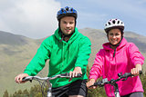 Smiling couple on a bike ride wearing hooded jumpers