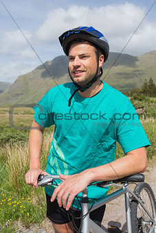 Fit man leaning on his mountain bike