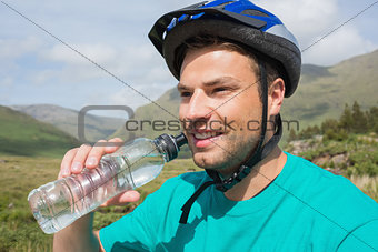 Fit man wearing helmet drinking water