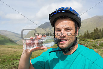 Fit man wearing bike helmet drinking water