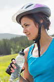 Fit woman wearing bike helmet holding water bottle