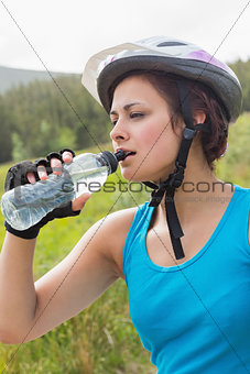 Fit woman wearing bike helmet drinking water